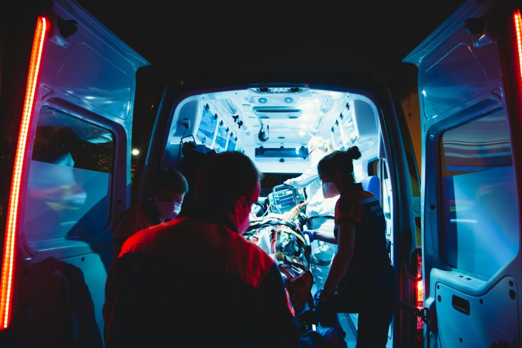 An Ontario ambulance sits idle as first responders escort a patient into the ambulance. The transportation is not covered by OHIP in 2025. The patient will have to pay out-of-pocket. 