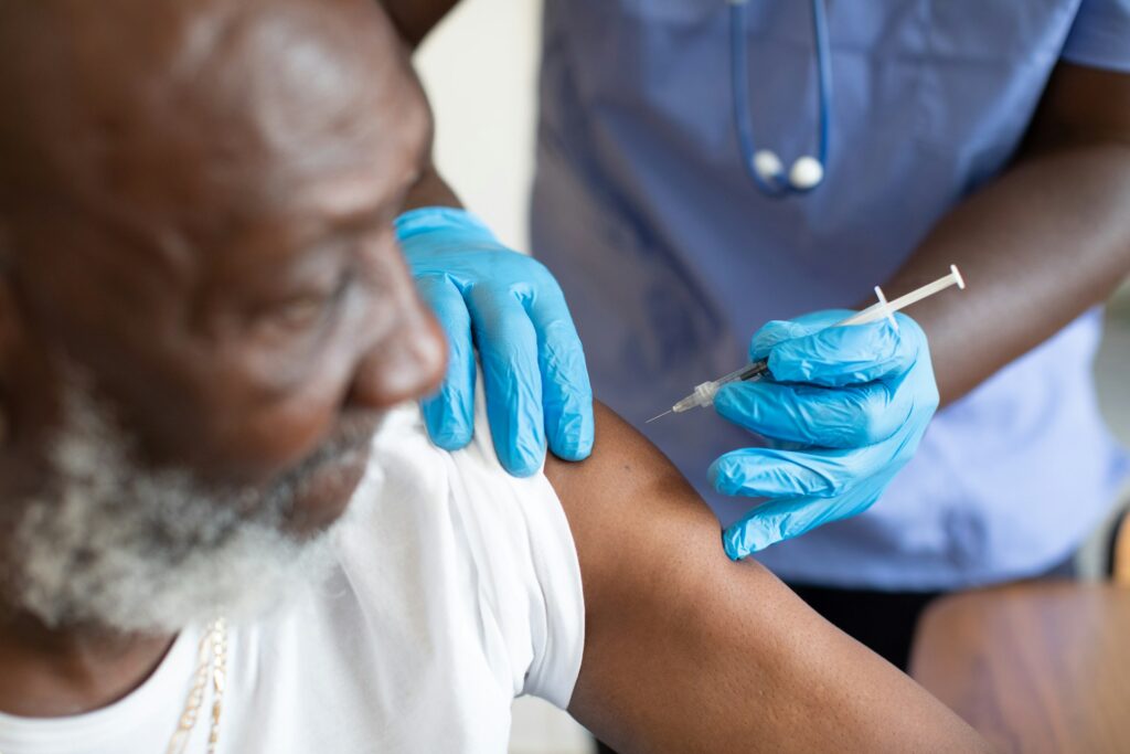 A health practitioner administers a shot to a man's upper arm, the shot is being covered by the man's individual health insurance plan in Ontario